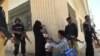 Pakistani policeman stand guard as a health worker administers polio drops to a child during a polio vaccination campaign after a day of an attack by gunmen in Karachi on April 21, 2016.