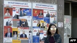 A woman walks past election posters on March 29, 2017 in Yerevan, ahead of April 2 parliamentary elections.