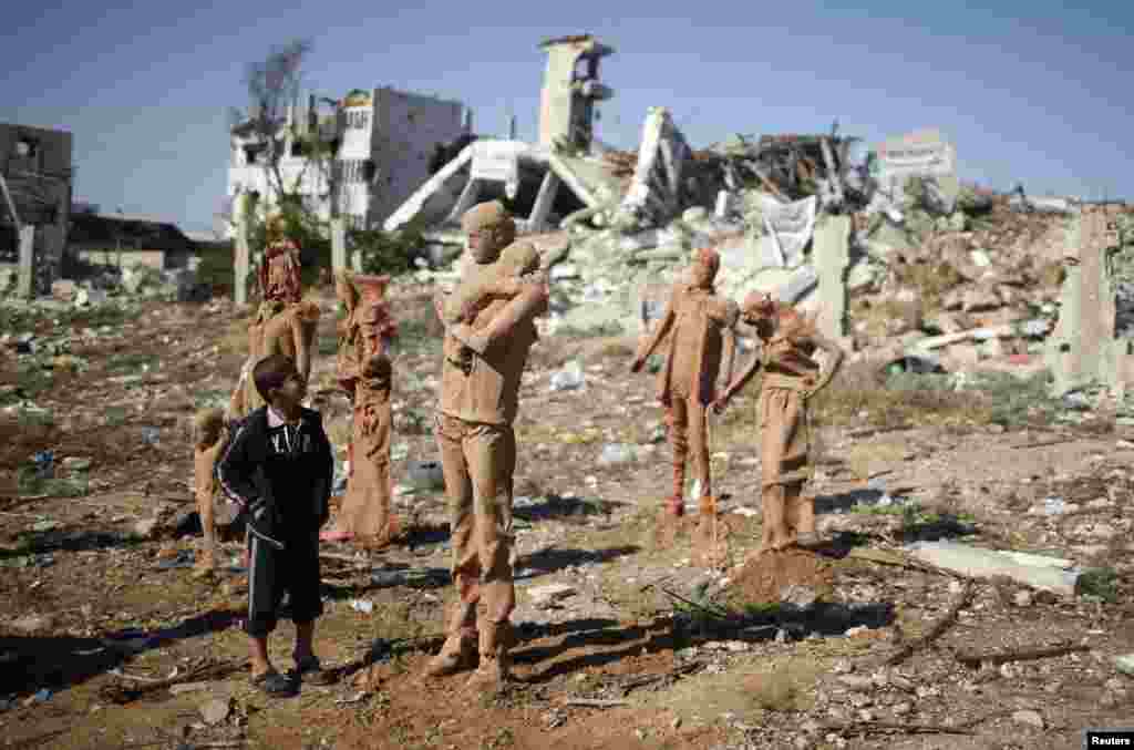 A Palestinian boy looks at statues made of fiberglass and covered with clay by Palestinian artist Eyad Sabbah, which are depictions of Palestinians who fled their houses from Israeli shelling during the most recent conflict, in Gaza City.