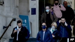 People walk down the steps of the main entrance of Waterloo train station, at which point they are allowed to remove their face coverings, in London, Oct. 15, 2020.
