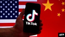 ARCHIVO - En esta ilustración fotográfica, el logotipo de la aplicación de redes sociales TikTok se muestra en la pantalla de un iPhone frente a una bandera de EEUU y un fondo de bandera china en Washington, DC, el 16 de marzo de 2023.