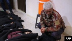A handout picture obtained from the Syrian Kurdish North Press Agency purportedly shows a Syrian man mourning as he looks at corpses lined up in a medical facility in Tal Rifaat, following a Turkish artillery attack on Dec. 2, 2019.