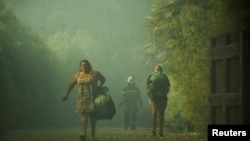 People carry their belongings following the spread of wildfires near Lautaro, Chile, Feb. 9, 2025 