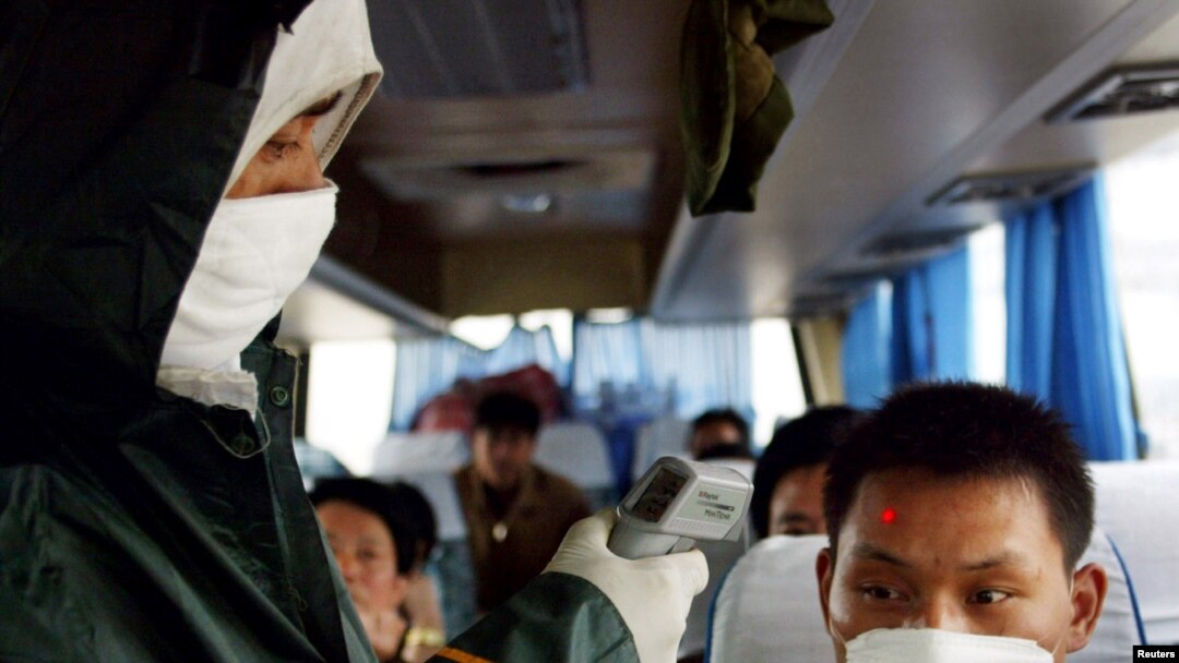 Seorang pekerja medis China memeriksa suhu seorang pendatang di sebuah pos pemeriksaan di jalan bebas hambatan menuju Wuhan, ibu kota provinsi Hubei, 10 Mei 2003. (Foto: Reuters)