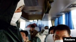 Seorang pekerja medis China memeriksa suhu seorang pendatang di sebuah pos pemeriksaan di jalan bebas hambatan menuju Wuhan, ibu kota provinsi Hubei, 10 Mei 2003. (Foto: Reuters)