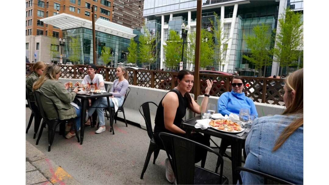 FILE - Patrons seated at outdoor tables at a restaurant converse and dine without masks, in Boston, May 2, 2021.