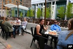 FILE - Patrons seated at outdoor tables at a restaurant converse and dine without masks, in Boston, May 2, 2021.