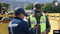 ARCHIVO - Un funcionario de Migración Colombia habla con un miembro de la Guardia Nacional Bolivariana.