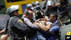 La policía peruana forcejea con un manifestante, durante la reubicación de los vendedores del mercado La Parada, en Lima, el sábado 27 de octubre de 2012.