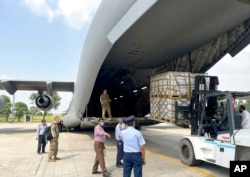 FILE - U.S. forces look on while local workers unload U.S. government relief sent to Pakistani people, at Noor Khan Air Base in Islamabad, Sept. 9, 2022. The State Department on Jan. 24, 2025, froze new funding for almost all U.S. aid programs worldwide.