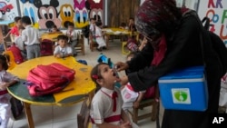 A health worker administers a polio vaccine to a child in a school in Karachi, Pakistan, Oct. 28, 2024. 