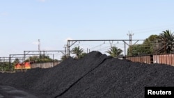 FILE - A Transnet Freight Rail train is seen next to tons of coal mined from the nearby Khanye Colliery mine, at the Bronkhorstspruit station, in Bronkhorstspruit, around 90 kilometers north-east of Johannesburg, South Africa, April 26, 2022.