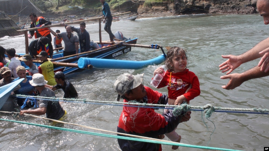 Seorang petugas menyelamatkan seorang anak yang menumpang kapal pembawa pencari suaka yang tenggelam di Jawa Barat (24/7). 