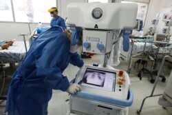 A healthcare worker wearing full protective gear looks at the chest X-ray of a patient in a ward reserved for COVID-19 patients at the Hospital Juarez, in Mexico City, June 26, 2020.