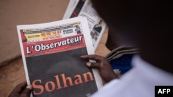 A man reads the 'L'Observateur Paalga' newspaper in Ouagadougou on June 7, 2021, about the attacks in Solhan, a village in Burkina Faso's volatile north.