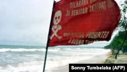 Bendera peringatan berkibar saat gelombang tinggi mencapai pantai sebagai ilustrasi. BMKG BMKG) mengeluarkan peringatan dini potensi lahirnya siklon tropis di sekitar Samudera Hindia, Barat Daya Lampung. (Foto: AFP/Sonny Tumbelaka)