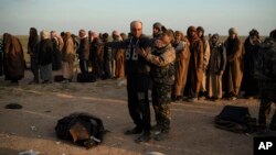 FILE - In this Feb. 22, 2019, file photo, a man is frisked by a U.S.-backed Syrian Democratic Forces fighter after being evacuated out of the last territory held by Islamic State militants, near Baghuz, eastern Syria. 