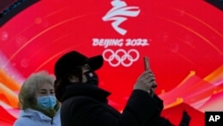 Dua orang perempuan berada di Beijing Medals Plaza of the Winter Olympics di Beijing, China, Senin, 3 Januari 2022. (Foto: AP/Ng Han Guan)