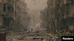 A child walks past damaged buildings in Deir al-Zor April 4, 2013. 