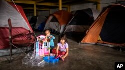 Dos niños de Honduras que esperan con sus familiares para solicitar asilo en EE.UU., juegan en el refugio en el centro de Tijuana, México, el martes 25 de diciembre de 2018.