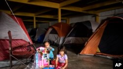 Los niños hondureños juegan con juguetes nuevos en un almacén vacío utilizado como refugio que abrió sus puertas a los migrantes en el centro de Tijuana, México. Foto de archivo.