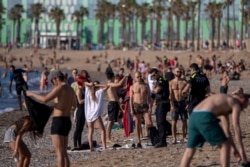 FILE - Police officers asks people to not sit while patrolling at the beach in Barcelona, Spain, May 20, 2020.
