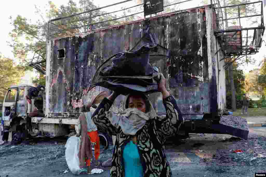 A woman carries recyclables from the burnt truck used by Bushra Bibi, wife of jailed former Pakistani Prime Minister Imran Khan, after security forces launched a raid on supporters of Khan&#39;s party Pakistan Tehreek-e-Insaf (PTI) who had stormed the capital demanding his release on Nov. 26, 2024, in Islamabad.&nbsp;