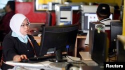 FILE - A woman browses the Internet at a cyber cafe in Kuala Lumpur.