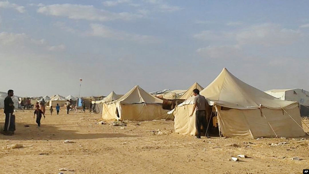 FILE - Syrians walk through the Ruqban refugee camp in Jordan's northeast border with Syria on June 22, 2016. Jordanian authorities announced Tuesday, Nov. 22, 2016, the resumption of aid to thousands of people, half of them children, who have been stuck with little food, water, medical care and other necessities since Jordan closed the border on June 21, 2016, to Syrian refugees. 