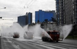 Vehicles spray disinfectant while sanitizing a street in Moscow, Russia, May 16, 2020.