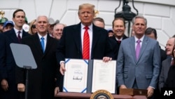 Presiden Donald Trump menunjukkan perjanjian perdagangan dengan Meksiko dan Kanada yang baru ia tandatangani hari Rabu (29/1) di Gedung Putih.