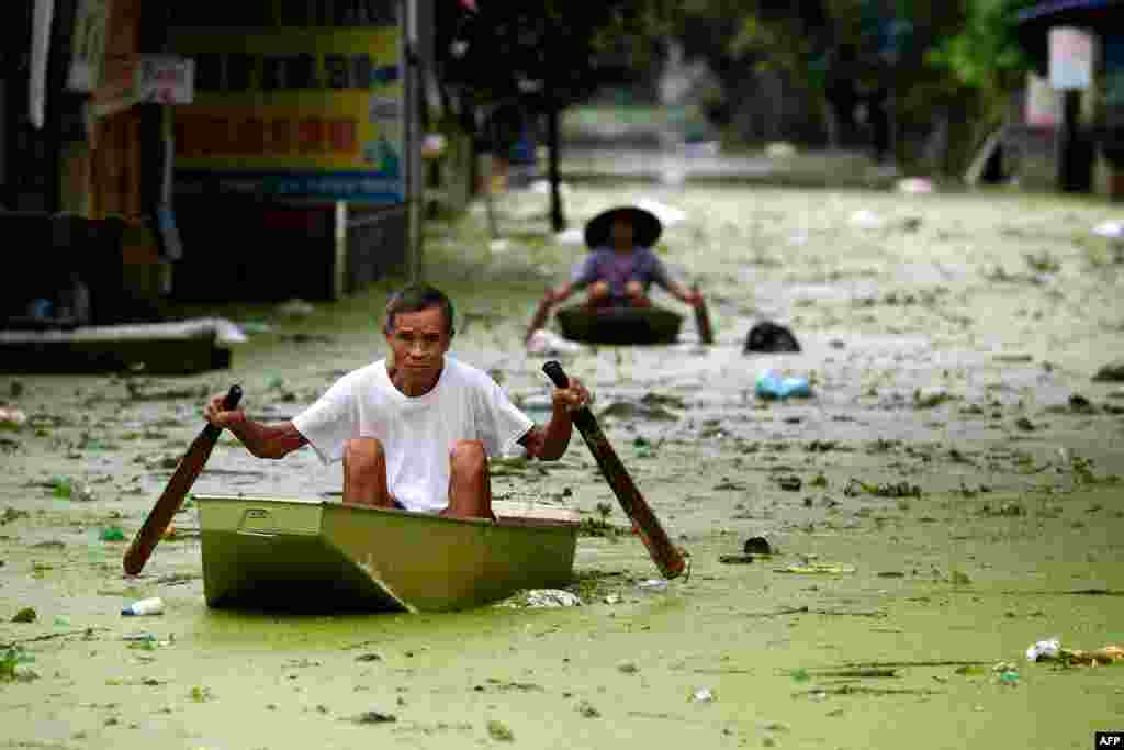 People take boats through floodwaters in Hanoi&#39;s suburban Chuong My district, Vietnam.