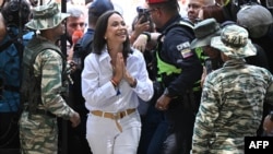 La dirigente de la oposición venezolana, María Corina Machado, saluda a electores, periodistas y personal de su centro de votación en Caracas, el 28 de julio de 2024.