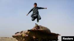 An Afghan boy jumps from the remains of a Soviet-era tank on the outskirts of Jalalabad, Afghanistan, Feb. 15, 2019. 