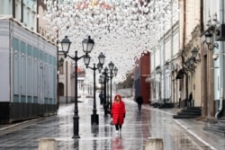 FILE - A woman walks through an almost empty pedestrian zone in Moscow, Russia, April 14, 2020, amid the coronavirus outbreak.