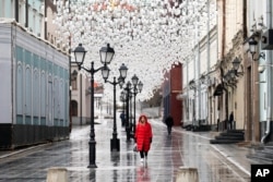 FILE - A woman walks through an almost empty pedestrian zone in Moscow, Russia, April 14, 2020, amid the coronavirus outbreak.