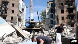 Volunteers clear the rubble of a destroyed building following a rocket attack the day beofre, in Kyiv, on July 9, 2024, amid the Russian invasion in Ukraine.