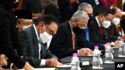 In this photo released by Malaysia's Department of Information, Prime Minister Ismail Sabri Yaakob, center, and opposition leader Anwar Ibrahim, left, sign documents during a ceremony at the parliament house in Kuala Lumpur, Sept. 13, 2021.