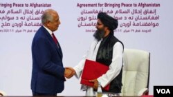 Utusan AS untuk urusan rekonsiliasi Afghanistan, Zalmay Khalilzad, dan Mullah Abdul Ghani Baradar, pemimpin delegasi Taliban berjabat tangan setelah penandatanganan perjanjian antara Taliban Afghanistan dan AS di Doha, Qatar, 29 Februari 2020. 