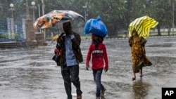 Indians walk in the rain in Kolkata, India, Nov. 9, 2019. Authorities in nearby Bangladesh put more than 50,000 volunteers on standby and readied about 5,000 shelters as Cyclone BulBul is expected to hit the low-lying nation's southern coast late Saturday