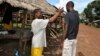 A community volunteer checks the temperature of a man before entering Jenewonde, in Liberia's Grand Cape Mount County, where local authorities say more than 20 people are suspected to have died of Ebola, Oct. 30, 2014.