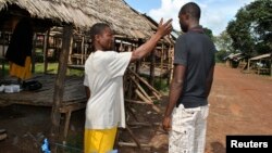 A community volunteer checks the temperature of a man before entering Jenewonde, in Liberia's Grand Cape Mount County, where local authorities say more than 20 people are suspected to have died of Ebola, Oct. 30, 2014.