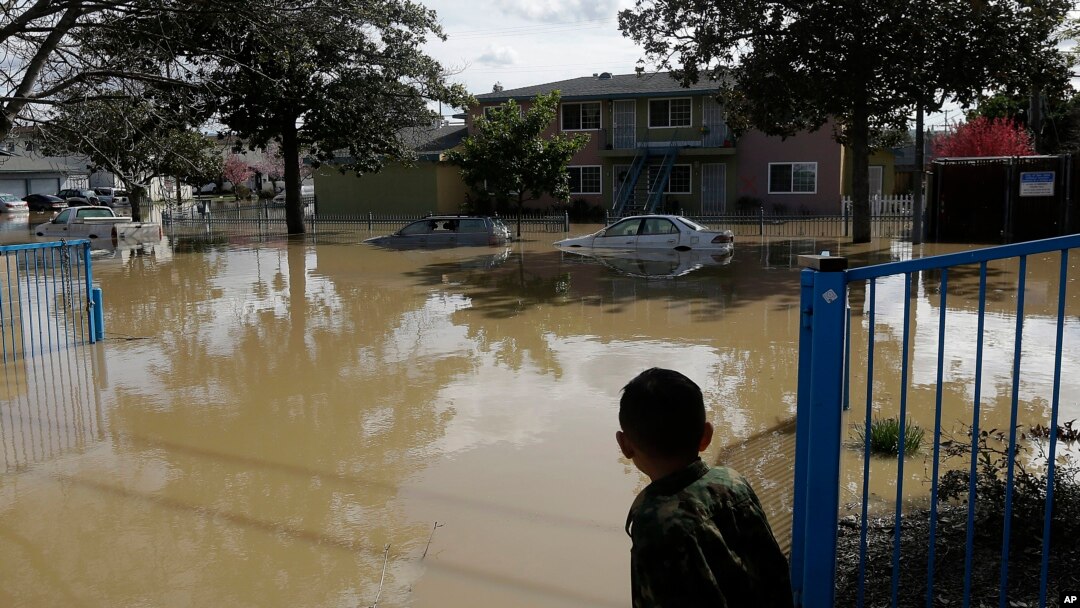 A boy looks onto flooded Nordale Avenue in San Jose, California, Feb. 22, 2017. Rising floodwaters sent thousands of residents fleeing inundated homes in San Jose and forced the shutdown of a major freeway.