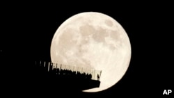 FILE - A supermoon rises behind an observation deck in New York City as seen from Hoboken, N.J., Friday, Nov. 15, 2024. (AP Photo/Seth Wenig)