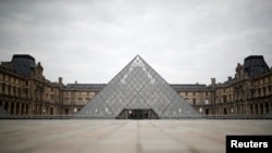 FILE - The area in front of the glass Pyramid of the Louvre museum in Paris is deserted as a lockdown is imposed to slow the rate of the coronavirus disease (COVID-19) in France, March 18, 2020.