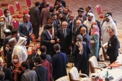 Abdullah Abdullah (C), chairman of Afghanistan's High Council for National Reconciliation, speaks with members of delegations at the end of a session during peace talks between the Afghan government and the Taliban, in Doha, Qatar, Sept. 12, 2020.