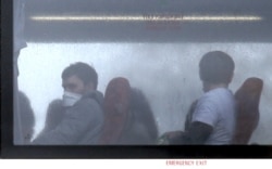 Passengers wearing face masks are seen aboard a convoy of buses carrying British nationals evacuated from Wuhan, China, after arriving in Milton Keynes, north of London, Feb. 9, 2020.