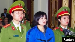 Vietnamese prominent activist Tran Thi Nga stands between police in the dock during her appeal trial in Phu Ly city, Vietnam Dec. 22, 2017. 