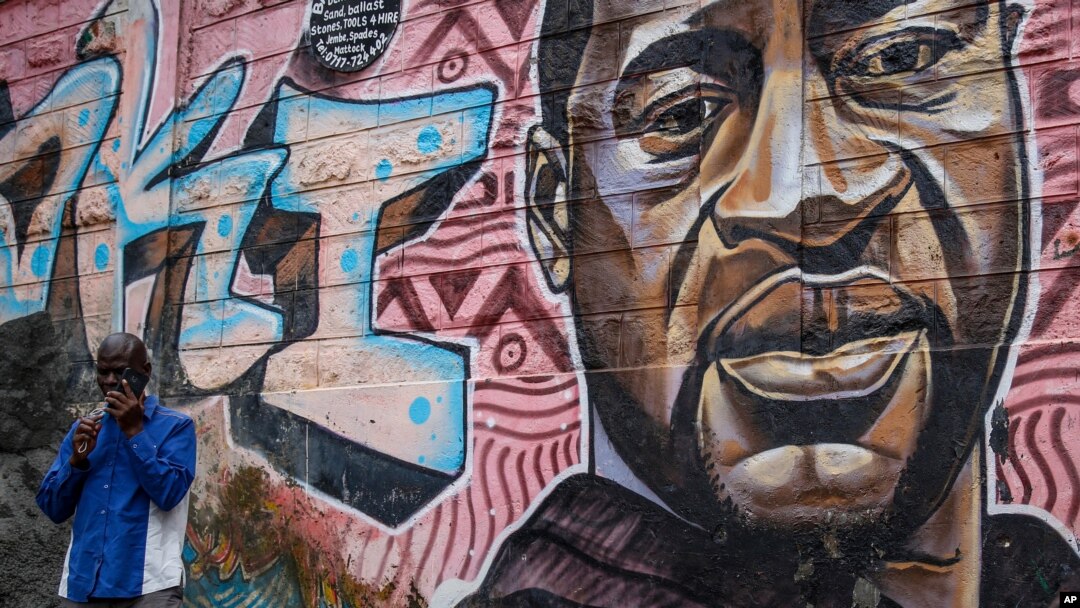 A local resident stands next to a mural showing George Floyd with the Swahili word "Haki" or "Justice" in the Kibera low-income neighborhood of Nairobi, Kenya, April 21, 2021.