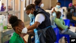 A professional paramedic receives a dose of Johnson & Johnson COVID-19 vaccine from a health staff member at a vaccination center at Chris Hani Baragwanath Academic Hospital in Johannesburg, South Africa, March 26, 2021. 